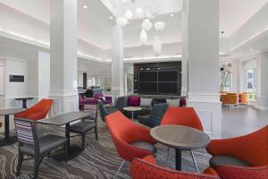 a lobby with tables and chairs and a tv at Hilton Garden Inn Jackson-Madison in Madison