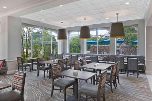 uma sala de jantar com mesas, cadeiras e janelas em Hilton Garden Inn Jackson-Madison em Madison