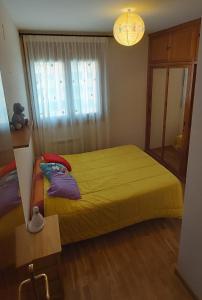 Un dormitorio con una cama amarilla y una ventana en Jaca Artaso, en Jaca