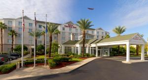 a hotel with palm trees in front of a building at Hilton Garden Inn Jacksonville Airport in Jacksonville