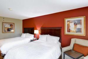 a hotel room with two beds and a chair at Hampton Inn Jacksonville - I-95 Central in Jacksonville