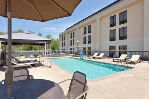 a swimming pool with chairs and a building at Hampton Inn Joplin in Joplin