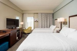 a hotel room with two beds and a flat screen tv at Hampton Inn Joplin in Joplin