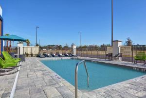 een groot zwembad met groene stoelen en een parasol bij Hampton Inn & Suites Middleburg, Fl in Middleburg