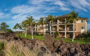 a large building with palm trees in the background at Hilton Grand Vacations Club Kings Land Waikoloa in Waikoloa