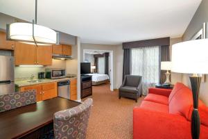 a kitchen and a living room with a red couch at Homewood Suites Lafayette in Lafayette