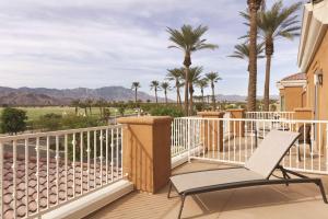 a balcony with a chair and palm trees at Homewood Suites by Hilton La Quinta in La Quinta