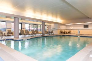 ein großer Pool in einem Hotel mit Stühlen und Tischen in der Unterkunft Hampton Inn & Suites East Lansing in Okemos