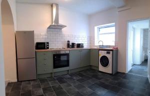 a kitchen with a stove and a washer and dryer at Emerald House - TV in every bedroom! in Neath
