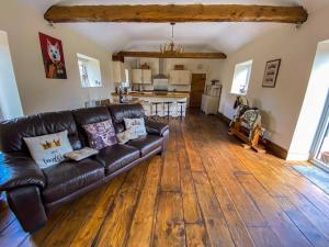 a living room with a leather couch and a kitchen at The Udderhouse - Udderly Unforgettable Retreat in Donyatt