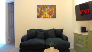 a living room with a couch and a painting on the wall at Emerald House - TV in every bedroom! in Neath