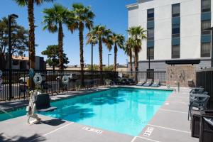 a swimming pool with palm trees and a building at Hampton Inn & Suites Las Vegas Airport in Las Vegas