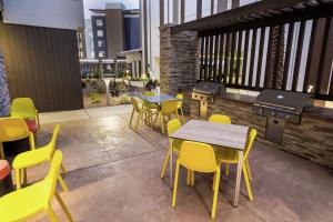 a patio with yellow chairs and tables and a grill at Home2 Suites by Hilton Las Vegas Stadium District in Las Vegas