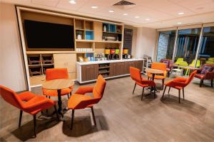 a waiting room with orange chairs and a flat screen tv at Home2 Suites by Hilton Las Vegas Stadium District in Las Vegas