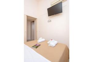 um quarto com uma cama com toalhas e uma televisão em Flora Maisonettes 2 em Gaios