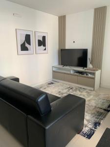sala de estar con sofá negro y TV de pantalla plana en Apto novo e bem localizado em Porto Belo - SC, en Porto Belo