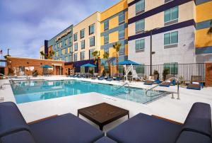 une piscine dans un hôtel avec des chaises et un bâtiment dans l'établissement Hampton Inn Las Vegas Strip South, NV 89123, à Las Vegas