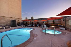 a pool at a hotel with tables and umbrellas at Hampton Inn & Suites Los Angeles Burbank Airport in Burbank