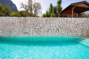 een stenen muur naast een zwembad bij Villa estilo Mediterráneo in Calpe