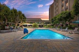 a swimming pool with chairs and a building at Doubletree by Hilton Whittier in Whittier