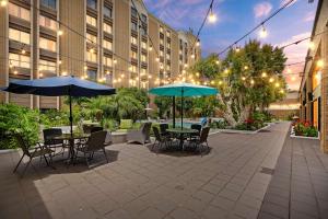an outdoor patio with tables and chairs and umbrellas at Doubletree by Hilton Whittier in Whittier