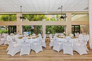 une salle de banquet avec des tables et des chaises blanches et de grandes fenêtres dans l'établissement Doubletree by Hilton Whittier, à Whittier