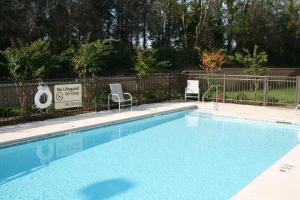 a swimming pool with two chairs and a fence at Hampton Inn & Suites Lebanon in Lebanon