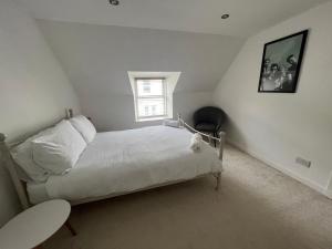 a white bedroom with a bed and a window at MaCaMor in Helmsdale