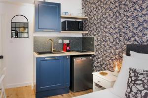 La cuisine est équipée de placards bleus et d'un réfrigérateur en acier inoxydable. dans l'établissement La Tour de Bohémond, à Carcassonne