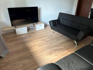 a living room with a black couch and a flat screen tv at Moderne Service Apartment AVD3 in Gelsenkirchen +3 photos