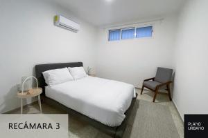 a bedroom with a white bed and a chair at Apartamento nuevo en Veracruz Centro in Veracruz