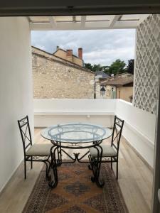 a glass table and two chairs on a balcony at maison blanche in Eymet