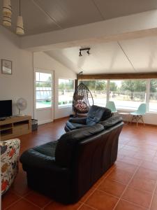 a living room with a black leather couch at Snow Guest House in Santarém