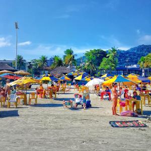 un grupo de personas sentadas en una playa con sombrillas en Dom Pedro 26, en Guarujá