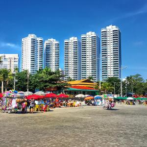 un grupo de edificios altos con mesas y sombrillas en Dom Pedro 26, en Guarujá