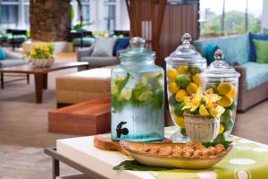 una mesa con dos jarras de cristal y un tazón de flores en Hilton Garden Inn Kauai Wailua Bay, HI en Kapaa