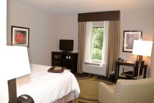 a hotel room with a bed and a chair and a window at Hampton Inn Maumelle in Maumelle