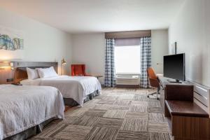 a hotel room with two beds and a flat screen tv at Hilton Garden Inn North Little Rock in North Little Rock