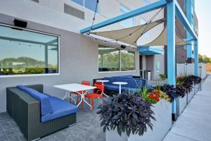 een patio met blauwe stoelen, tafels en ramen bij Tru By Hilton Denver, PA in Denver