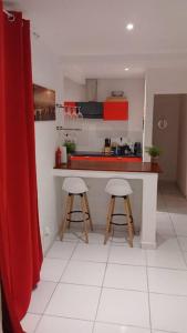 eine Küche mit einer Theke und 2 Hockern in einem Zimmer in der Unterkunft Jolie petite maison tout équipée in Le Gosier
