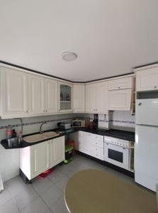 uma cozinha com armários brancos e electrodomésticos brancos em Ático en Barbate em Barbate