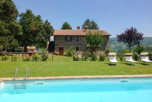 a swimming pool in front of a stone house at Casale Donatelli in Radicofani