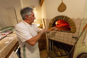 a man standing in a kitchen putting something into an oven at Casale Donatelli in Radicofani