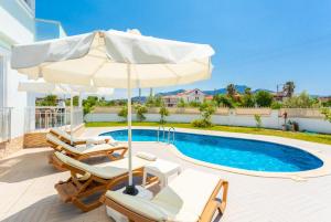 una piscina con sedie e ombrellone accanto a una piscina di Villa Veli a Dalyan