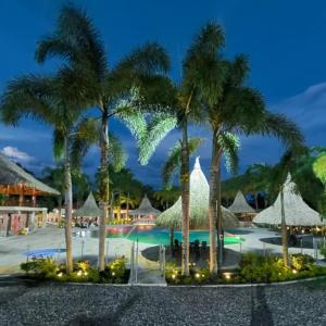 ビリャビセンシオにあるHOTEL CAMPESTRE Palmaのヤシの木と傘が備わるプール付きのリゾートです。