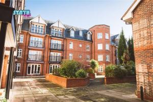 un gran edificio de ladrillo rojo con muchas ventanas en Spacious Central Leatherhead Apt Long Term Stay en Leatherhead