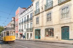un tramway jaune dans une rue urbaine avec des bâtiments dans l'établissement Aurore Duplex - New Apartment, à Lisbonne