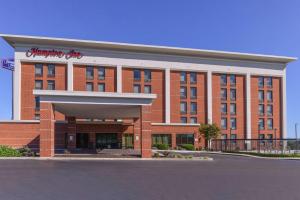 a large red brick building with a shopping center at Hampton Inn Martinsburg in Martinsburg