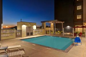a swimming pool with chairs and a building at Home2 Suites By Hilton Turlock, Ca in Turlock