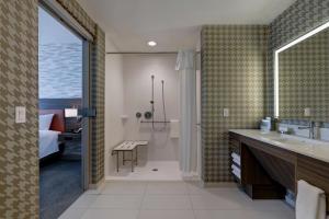 特洛克Home2 Suites By Hilton Turlock, Ca的一间带水槽和淋浴的浴室以及一间卧室